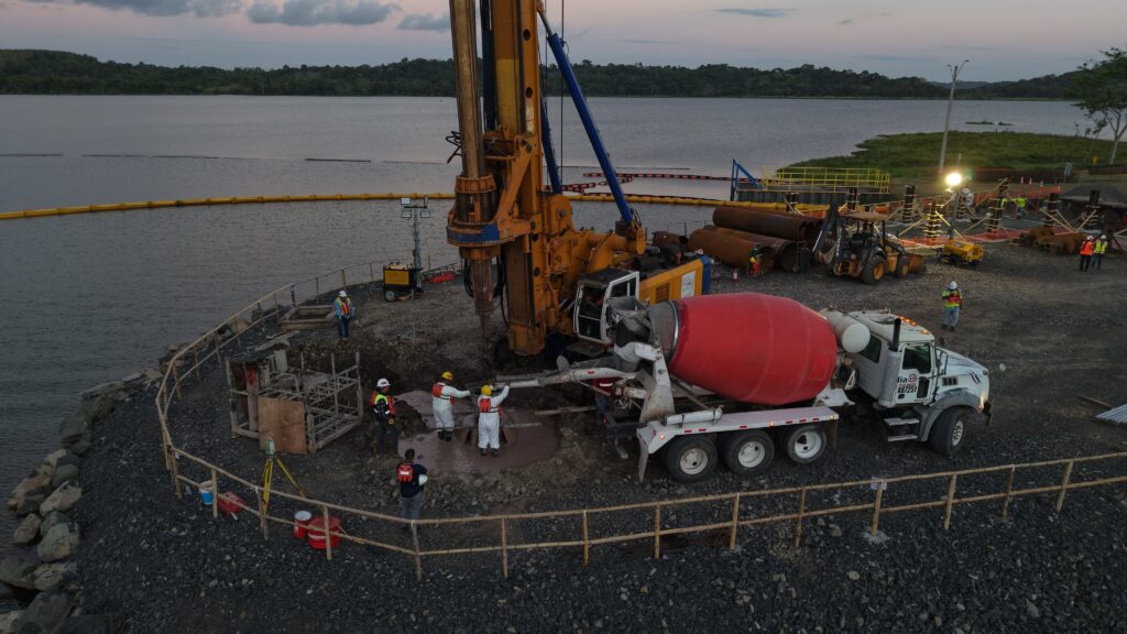 Vaciado de pilotes con concreto en obra de infraestructura hídrica en Panamá, con maquinaria pesada y equipo técnico en campo.