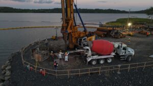 Vaciado de pilotes con concreto en obra de infraestructura hídrica en Panamá, con maquinaria pesada y equipo técnico en campo.